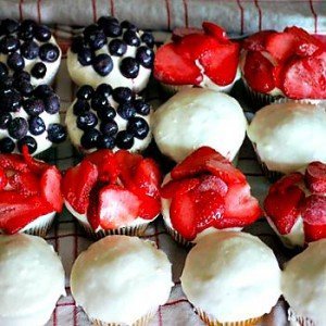vanilla cupcakes with toppings of blueberries, sliced strawberries and simple cream cheese frosting arranged in a USA flag pattern