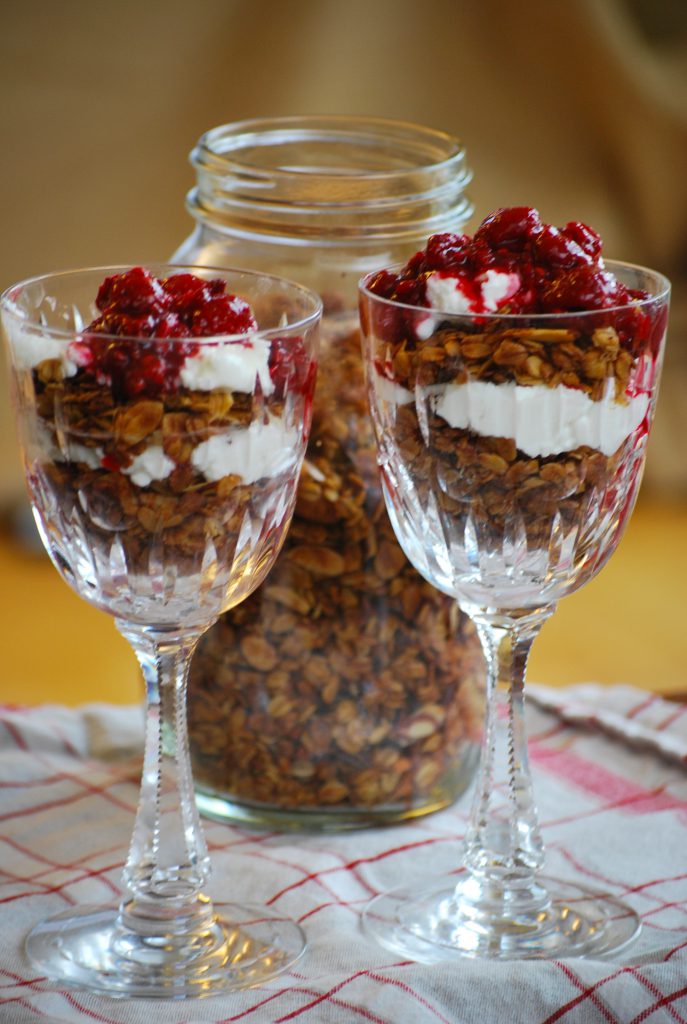 granola topped with alternating layers of yogurt and raspberry sauce