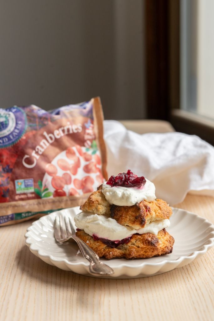 a hero shot of a cranberry shortcake with vanilla whipped cream and a bag of Stahlbush Island Farms frozen cranberries
