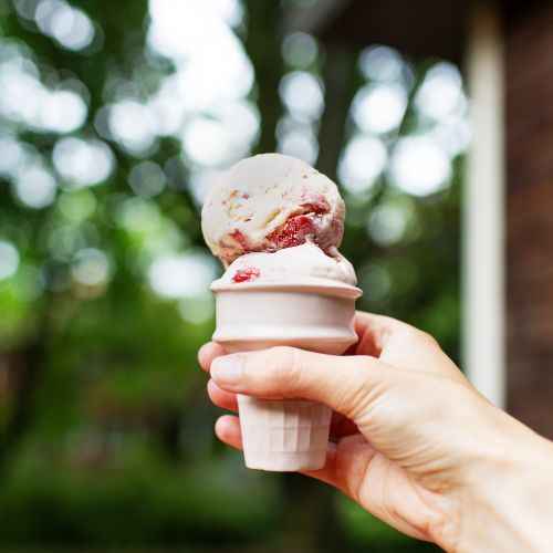 an ice cream cone with scoops of strawberry cheesecake ice cream