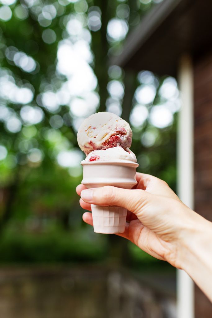 an ice cream cone with scoops of strawberry cheesecake ice cream
