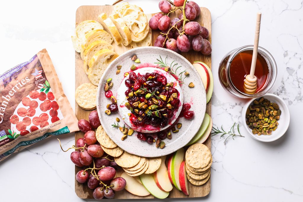 a charcuterie style spread on a wooden board with a baked brie with cranberry compote