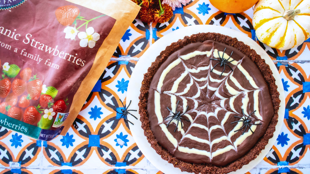 a chocolate tart with a white chocolate spider web and a strawberry filling