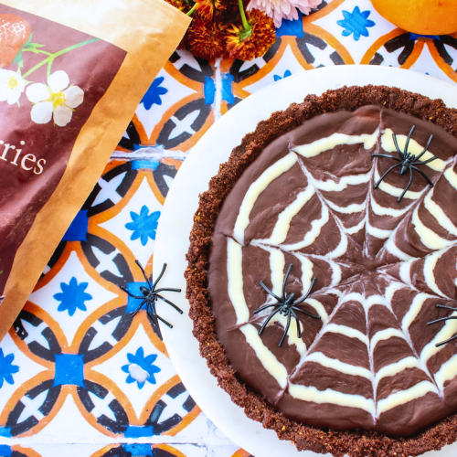 a chocolate tart with a white chocolate spider web and a strawberry filling