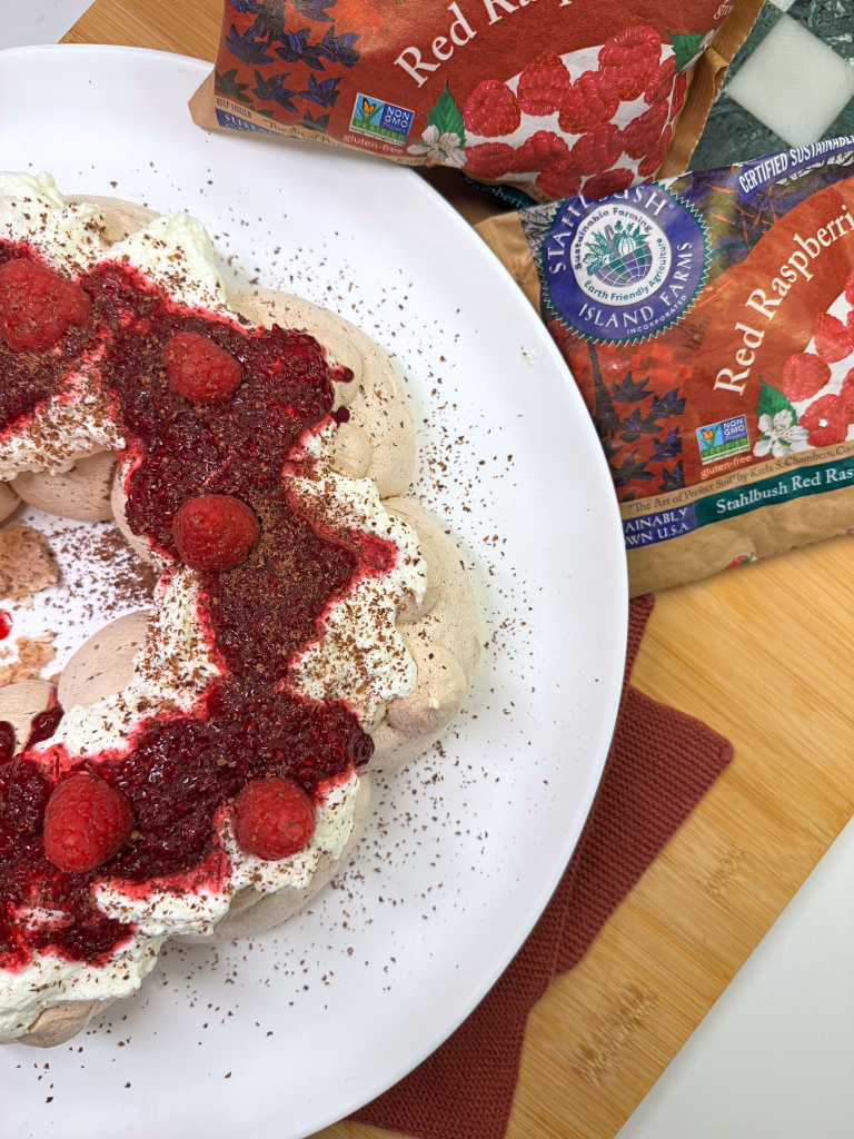 a chocolate pavlova wreath with raspberry jam with a bag of Stahlbush Island Farms Frozen Raspberries